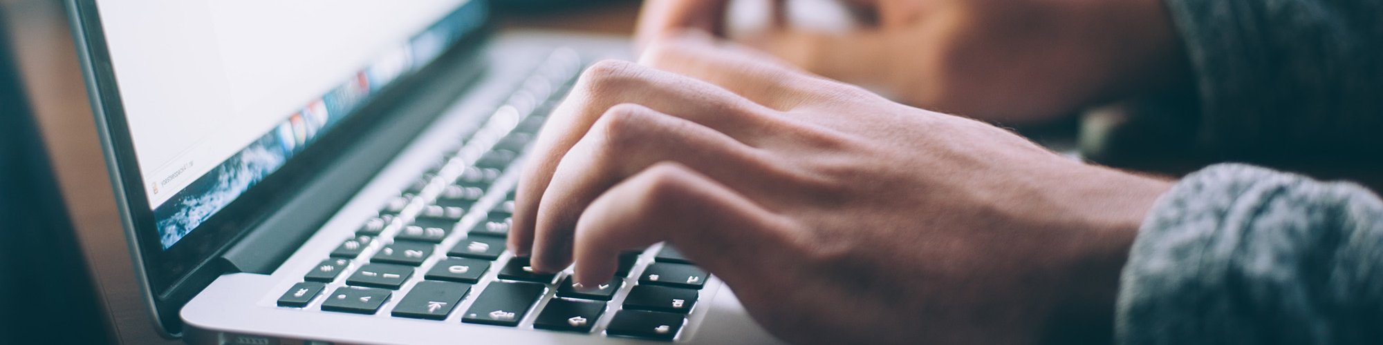 view of hands typing on a laptop keyboard